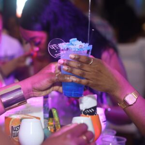 A blue cocktail being handed over a table at MUKE Life's All White Soiree